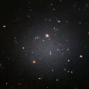 NGC 1052-DF2 réside dans le groupe dominé par une galaxie elliptique massive appelée NGC 1052. Cette grande galaxie à l&#39;apparence floue est si diffuse que les astronomes peuvent voir clairement les galaxies lointaines derrière elle.&amp;nbsp;Hubble a pris cette image le 16 novembre 2017 en utilisant son&amp;nbsp;Advanced Camera for Surveys. © Nasa, ESA et P. van Dokkum (université de Yale)