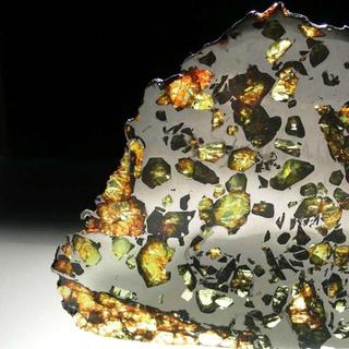Une coupe de la météorite d'Esquel. C'est une pallasite trouvée en 1951 dans la province de Chubut, en Argentine. Elle est constituée d’une trame de fer et de nickel dans laquelle se détachent des grains d’olivine. La pallasite provient de l’interface noyau-silicate d'un gros astéroïde, là où les silicates des couches profondes flottent dans la matrice de fer. Esquel est certainement la plus belle des pallasites.&nbsp;©&nbsp;www.carionmineraux.com