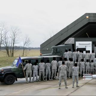 Soldados americanos estacionados na Base Aérea de Volkel, na Holanda, posam em frente ao que pode ser um míssil nuclear. © Bellingcat