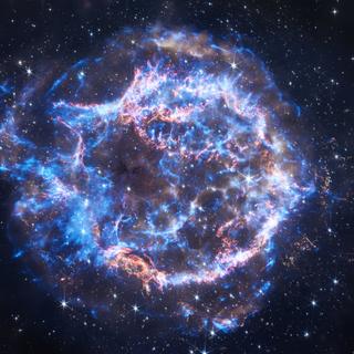 L’observatoire à rayons X Chandra de la Nasa a observé Cassiopée A pendant plus de 2 millions de secondes au total depuis ses « premières images lumineuses » du reste de supernova le 26 août 1999. Cas A se trouve à environ 11 000 années-lumière de la Terre. Les rayons X de Chandra sont représentés en bleu et combinés avec des images infrarouges du télescope spatial James-Webb de la Nasa en orange et blanc. © Rayons X : NASA/CXC/SAO ; Infrarouge : NASA/ESA/CSA/STScI/D. Milisavljevic (Université Purdue), I. De Looze (Université de Gand), T. Temim (Université de Princeton) ; Traitement d’images : NASA/CXC/SAO/J. Schmidt, K. Arcand et J. Major