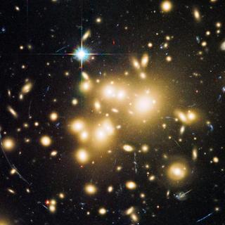 La présence de la matière noire dans les amas galactiques peut être déduite de l'effet de lentille gravitationnelle forte qu'elle génère, comme sur cette image prise par Hubble de l'amas Abell 1689 montrant des arcs lumineux. Il se pourrait que la lumière soit déviée, ironiquement, parce que l'amas contient des photons noirs. © Nasa