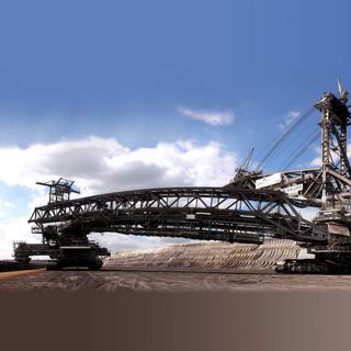  240 mètres de long et 96 mètres de hauteur pour un poids total de 13 500 tonnes. Chacune de ces machines peut dégager environ 240 000 tonnes de terre par jour. Chacun des 18 godets peut contenir 6,6 tonnes de matériaux. Avec leurs 12 chenilles de 3,8 mètres de large chacune, les excavatrices peuvent avancer de 10 mètres par minute. © Martin Röll, CC by-sa 2.5