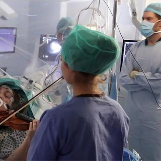 Uma violinista toca durante uma cirurgia no cérebro para orientar os cirurgiões a salvar sua mão. © King's College Hospital, AFP