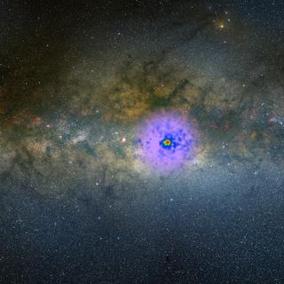 As observações do Fermi mostram um excesso de raios gama no coração da Via Láctea. Eles estão sobrepostos em cores falsas a uma imagem visível nesta montagem fotográfica. © NASA