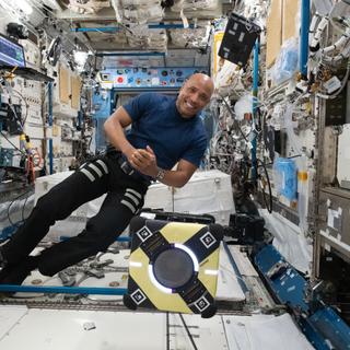 O astronauta da NASA e engenheiro de voo da Expedição 64, Victor Glover, trabalha com o robô Astrobee a bordo da estação espacial para testar um adesivo para agarramento e manipulação robótica como parte do experimento Astrobee/Gecko-2. © NASA