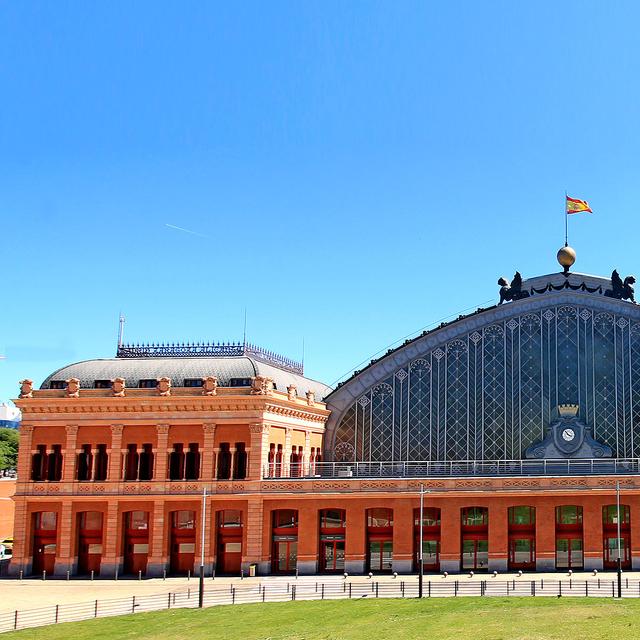 La gare d&#39;Atocha se dresse dans la capitale de l&#39;Espagne, Madrid. Inaugurée en 1851, elle était la première gare de Madrid et a été instaurée par la reine Isabelle II, à l&#39;instar de deux autres gares madrilènes : Delicias et celle du Nord. Quant à la gare d&#39;Atocha, ravagée par un incendie quelques dizaines d&#39;années plus tard, elle a été reconstruite en fer entre 1888 et 1892. Face à l&#39;entrée de la gare, un mémorial a été érigé en hommage aux quelque 200 personnes tuées dans l&#39;attentat du 11 mars 2004.© Luis García, CC by-sa&amp;nbsp;4.0